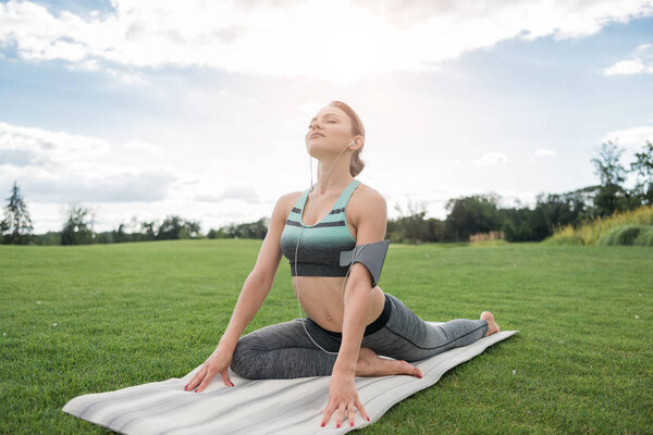 woman in earphones practicing yoga