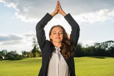 businesswoman meditating in park clipart
