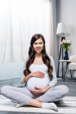 Pregnant woman sitting in lotus pose clipart
