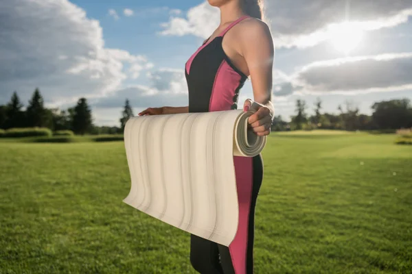 Женщина в спортивной одежде держит коврик для йоги — стоковое фото