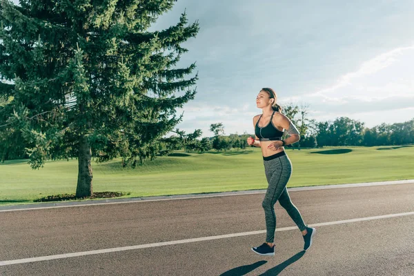 Спортивная бегущая женщина в наушниках — стоковое фото