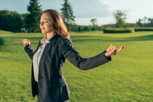 Souriante femme d'affaires méditant dans le parc — Photo