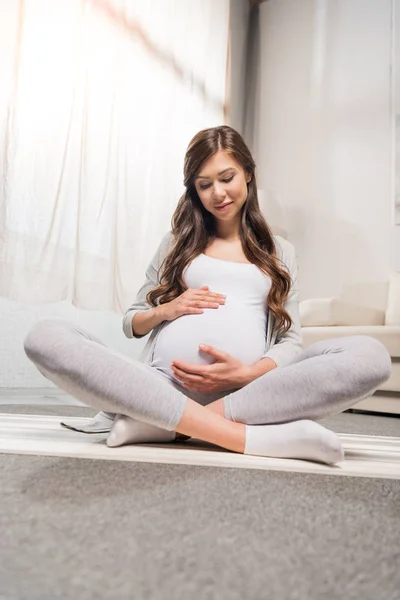 Беременная женщина сидит в позе лотоса — стоковое фото