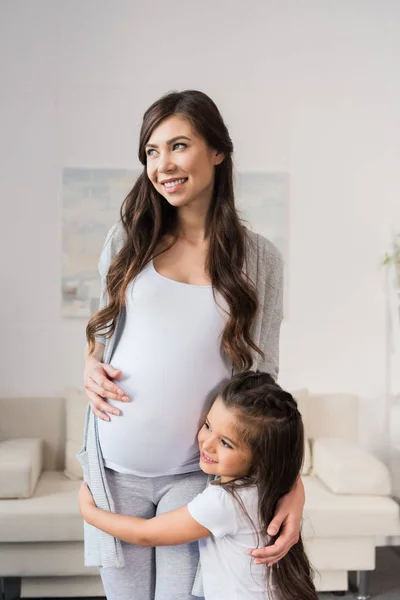 Chica abrazando embarazada madre — Foto de Stock