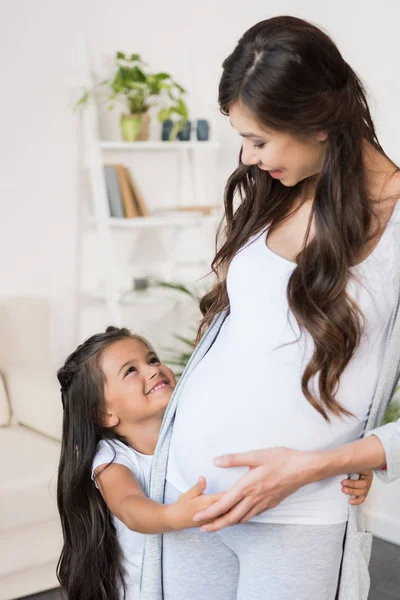 Kleines Mädchen berührt schwangeren Bauch — Stockfoto