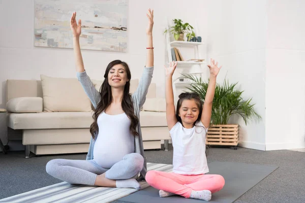 Pregnant woman with daughter in lotus pose — Stock Photo, Image