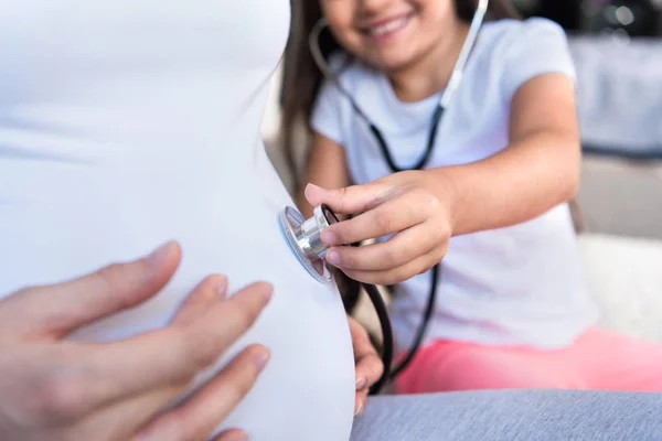 Girl listening to pregnant belly — Free Stock Photo