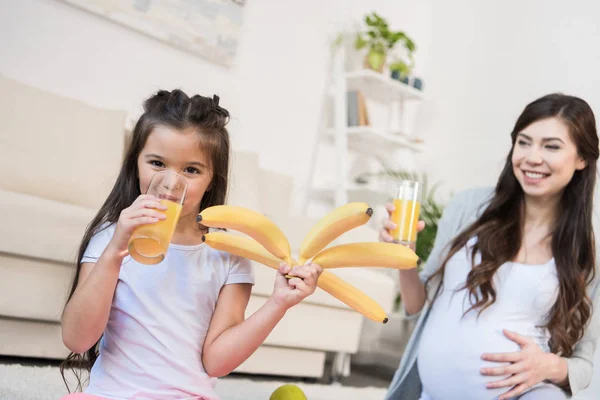 Menina segurando bananas e beber suco — Fotografia de Stock
