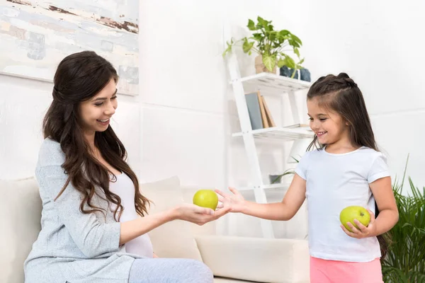 Mãe grávida dando maçã à filha — Fotografia de Stock