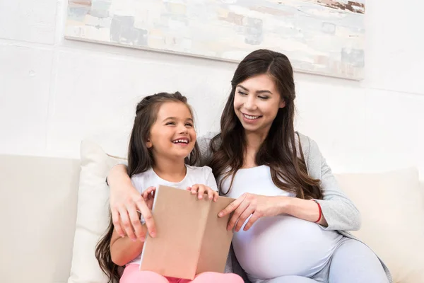 Little girl sitting on couch with mother — Stock Photo, Image