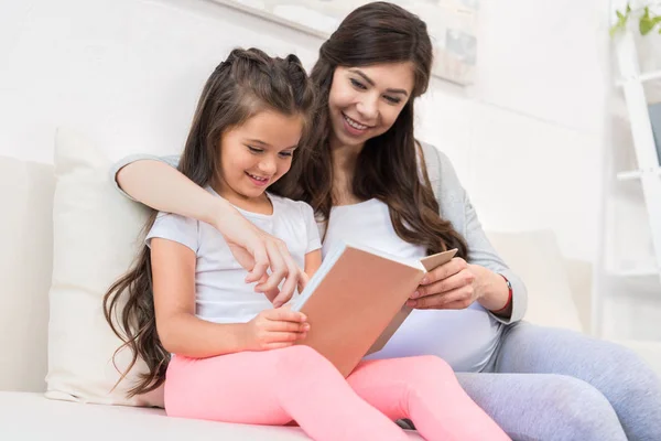 Niña leyendo libro con madre — Foto de Stock