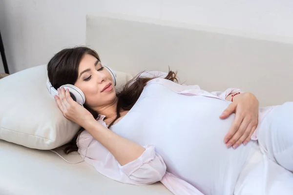 Pregnant woman in big headphones — Stock Photo, Image