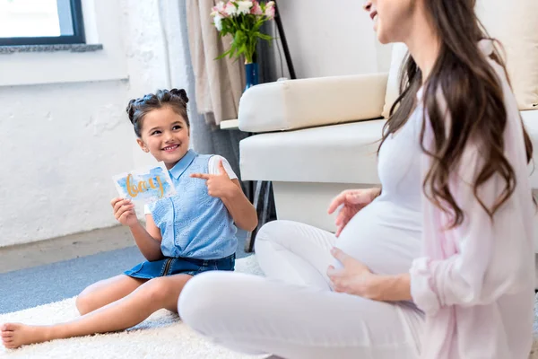 Vrouw met dochter bedrijf wenskaart — Stockfoto