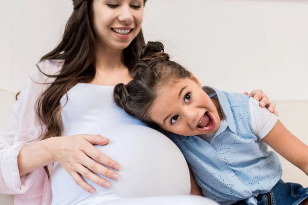 Chica escuchando el vientre de la madre embarazada — Foto de Stock