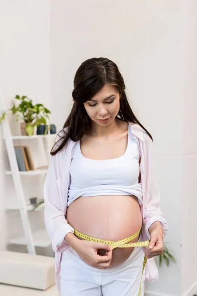 Pregnant woman with flexible ruler — Free Stock Photo