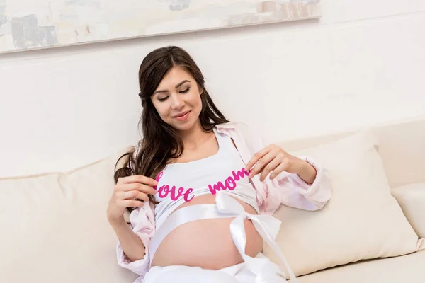 Mulher grávida segurando palavras amor mãe — Fotografia de Stock