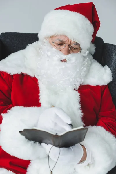Santa claus writing in notebook — Free Stock Photo
