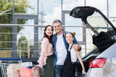 Aile araba yanındaki alışveriş sepeti ile