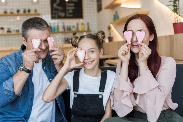 Família cobrindo olhos com biscoitos — Fotografia de Stock