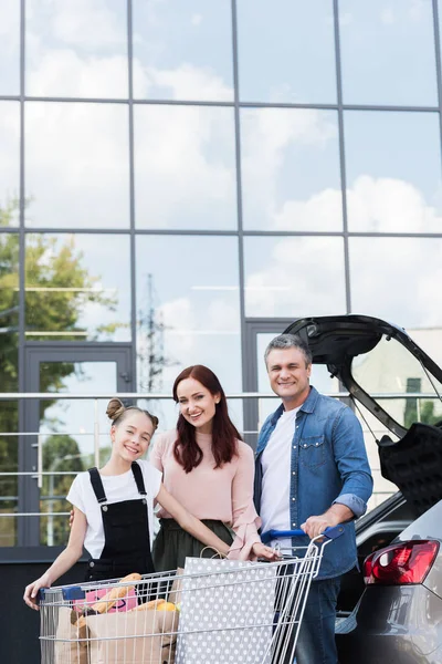 Aile araba yanındaki alışveriş sepeti ile