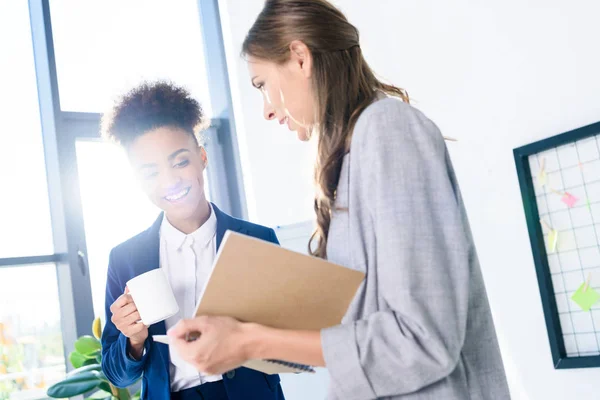 Young businesswomen with coffee and notebook — Free Stock Photo