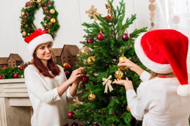 Anne ve kızı Noel ağacı süslüyorlar.