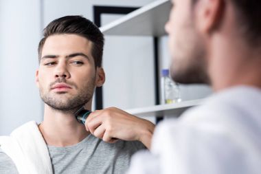 man shaving with electric trimmer clipart