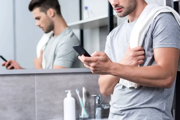 Mann benutzt Smartphone im Badezimmer — Stockfoto