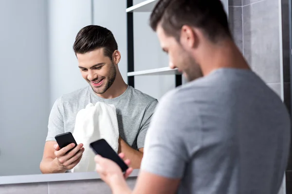 Man using smartphone in bathroom — Stock Photo, Image