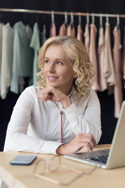 Businesswoman with laptop in clothing store — Stock Photo, Image