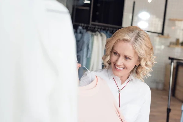Woman choosing clothes in clothing store — Stock Photo, Image