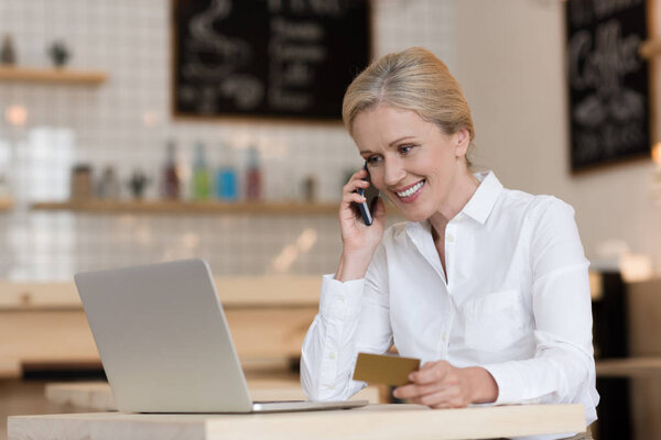 businesswoman with credit card talking on smartphone