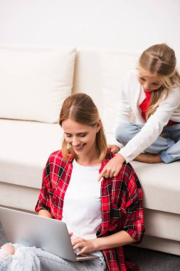 Anne ve kızı dizüstü bilgisayar kullanıyor.