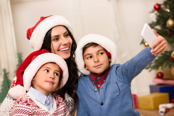 Famiglia a Babbo Natale cappelli prendendo selfie — Foto Stock