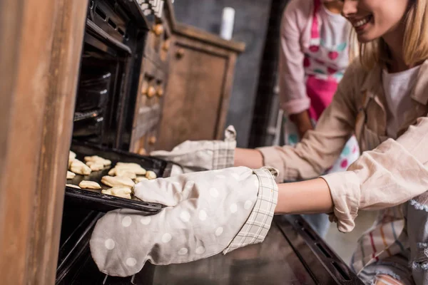Mulher colocando biscoitos crus no forno — Fotografia de Stock