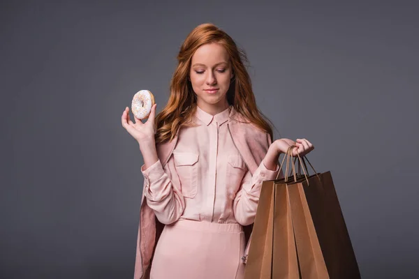 Lady with donut and shopping bags — Stock Photo, Image