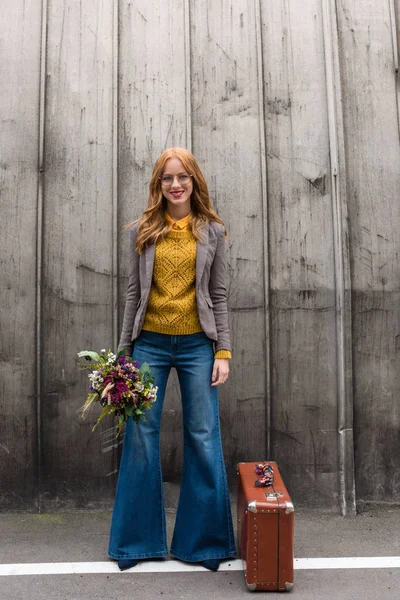 Niña sonriente con flores y maleta — Foto de Stock