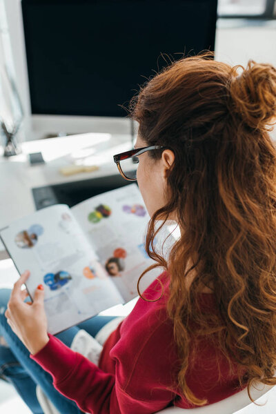 woman reading magazine in office