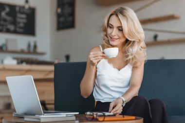 woman drinking coffee and using laptop clipart