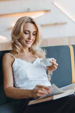 Kitap okuma ve kahve içme kadın