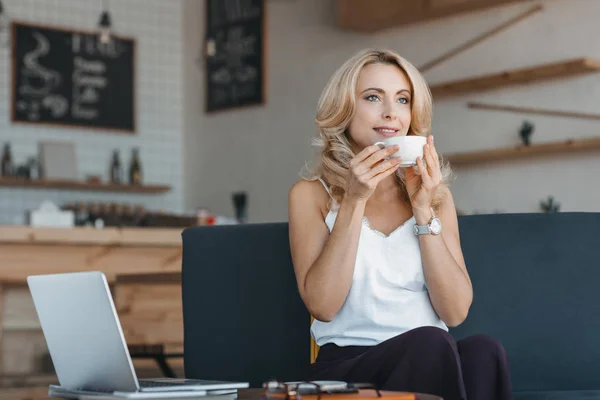 Femme buvant du café et utilisant un ordinateur portable — Photo