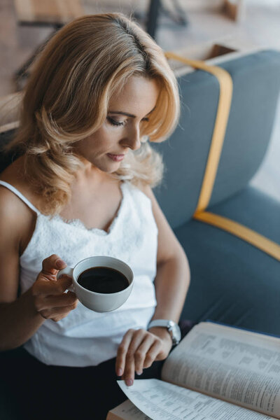 woman drinking coffee and reading book