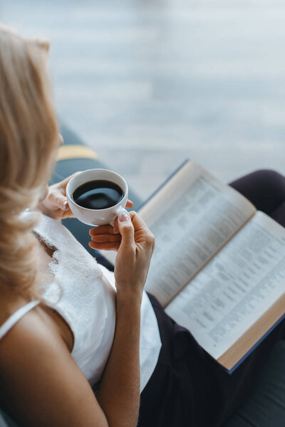 woman reading book and drinking coffee 