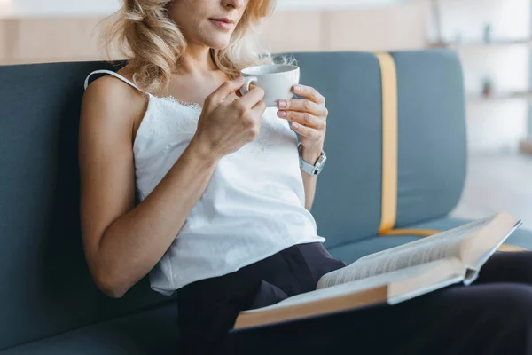 Frau liest Buch und trinkt Kaffee — Stockfoto