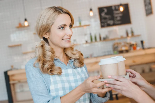 Serveerster holding wegwerp koffie kopjes — Stockfoto