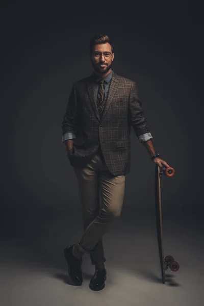 Man in suit posing with skateboard — Stock Photo, Image