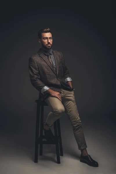 Homme sophistiqué en costume assis sur un tabouret — Photo