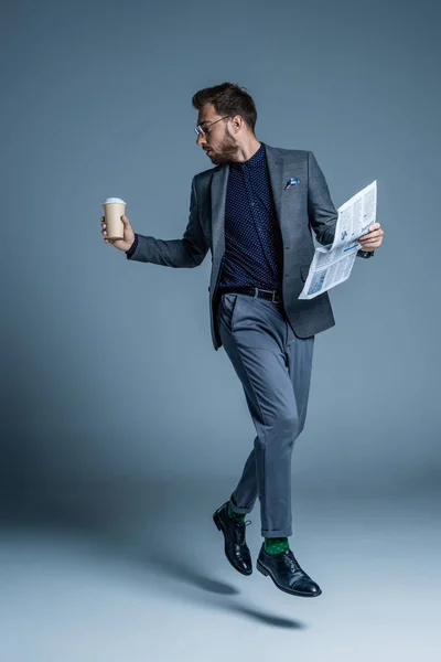 Бизнесмен ходит с кофе и газетой — стоковое фото