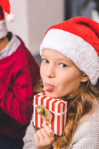 Girl with christmas gift showing tongue — Free Stock Photo