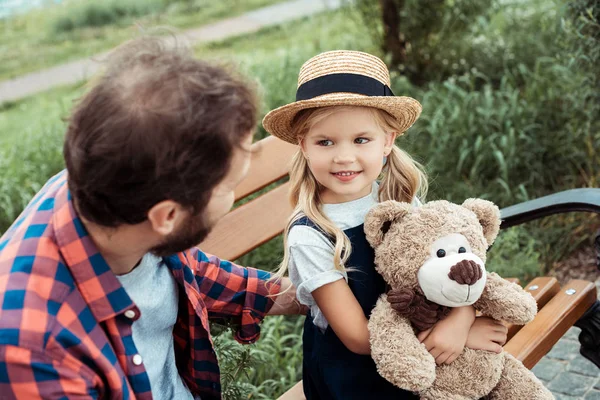 Family sitting on bench in park — Stock Photo, Image